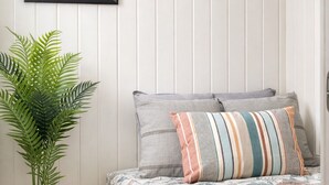 A bedroom with a bed, pillows, a framed picture, and a potted plant. - Rygge Apartments (Moss)
