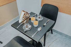 A dining table set with a fork, spoon, two glasses of orange juice, a small cup of coffee, and a decorative item. - Casa Loredana (Venice)