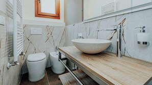 Uma casa de banho moderna com uma bacia grande, sanita e bidé.