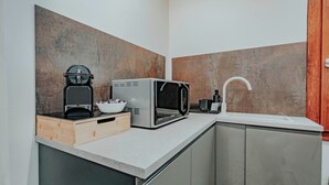 Cozinha moderna com micro-ondas, cafeteira e pia.