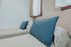 Een bed met een blauw kussen en een kleiner bed met een blauw kussen.
