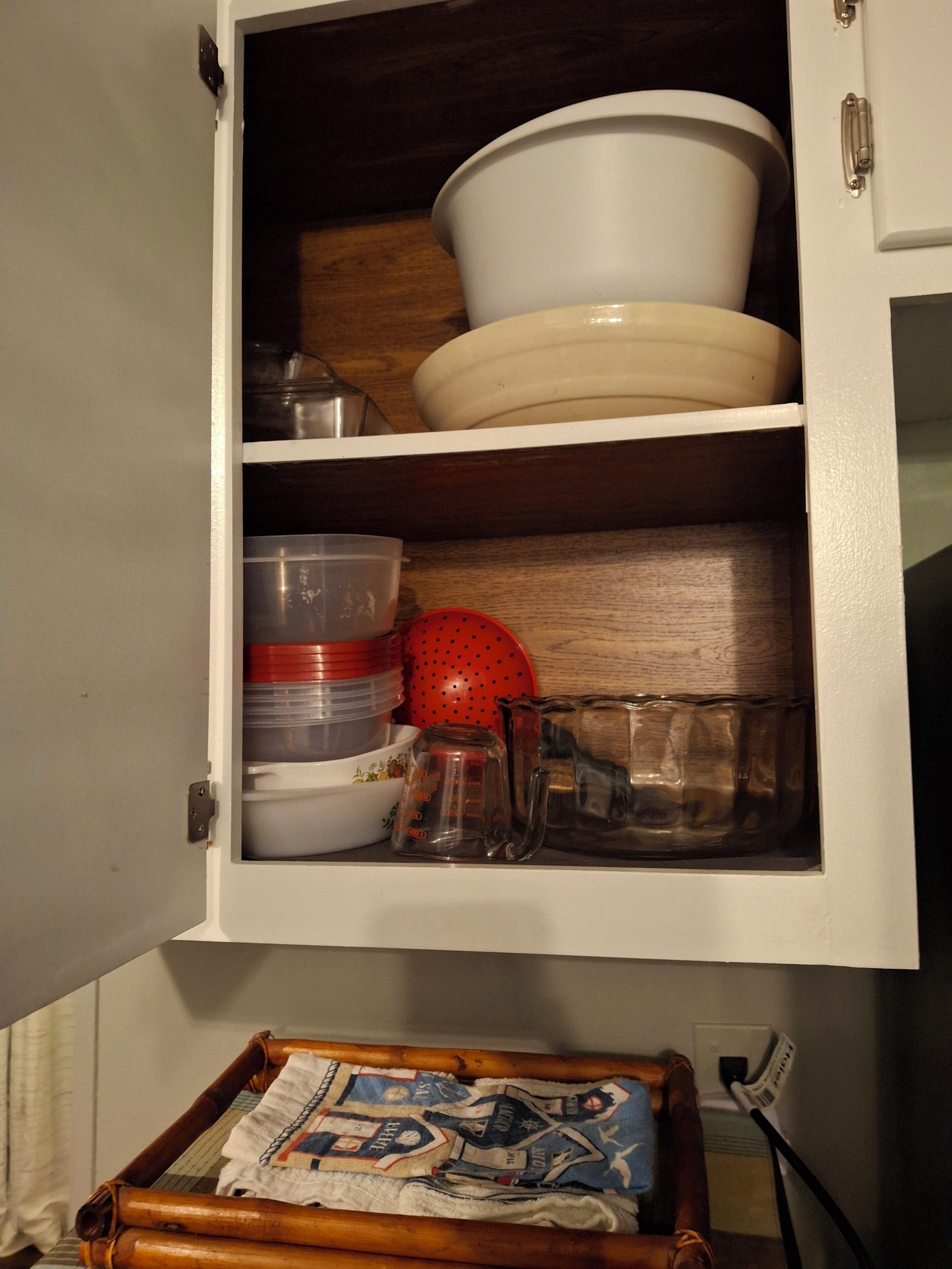 Ein Küchenschrank mit Stauraumregalen, einer Holztablett und einer Steckdose.