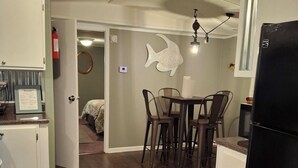 Een compacte keuken met een eethoek, een koelkast en een visdecoratie aan de muur.