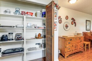 A kitchen with white shelves, wooden cabinets, and a dining area with a wooden table and chairs. - Lakefront Frostproof Retreat with Private Beach (Frostproof)