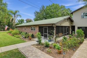 A residential property with a brick house, a covered porch, and a landscaped garden. - Lakefront Frostproof Retreat with Private Beach (Frostproof)