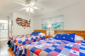 A bedroom with two beds, a ceiling fan, a window with blinds, and a wall decoration. - Lakefront Frostproof Retreat with Private Beach (Frostproof)