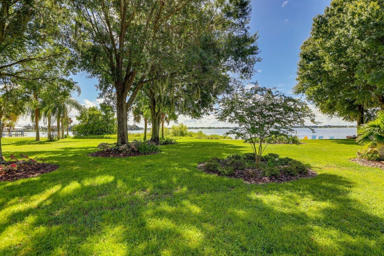 A well-maintained grassy area with trees and a view of a body of water.