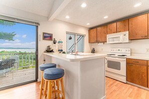 A modern kitchen with a central island, wooden cabinets, a microwave, and an oven. - The Homestead Glen Arbor Condo Lake Michigan (Glen Arbor)