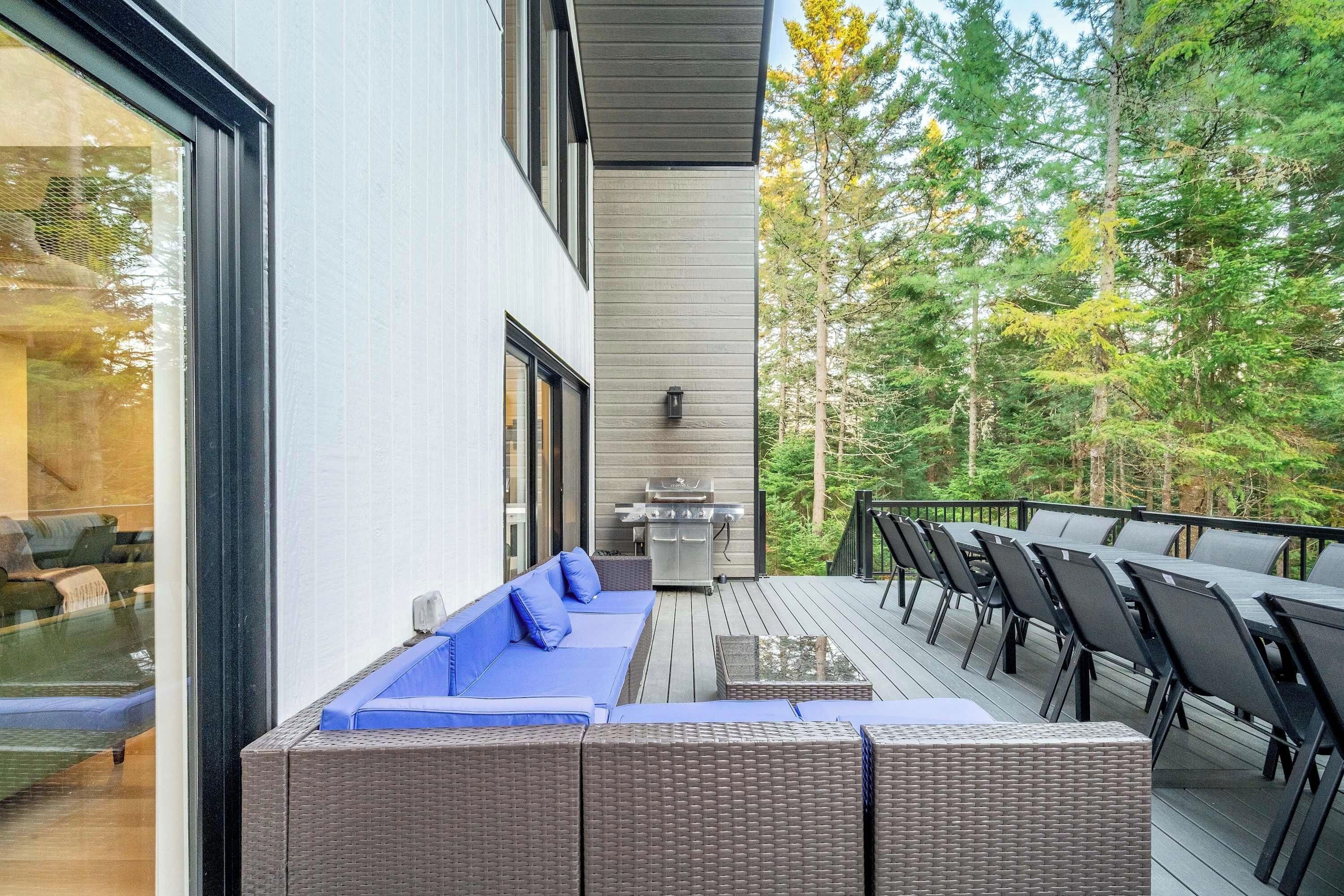Une terrasse extérieure moderne, dotée d’un barbecue intégré et d’un espace salon.