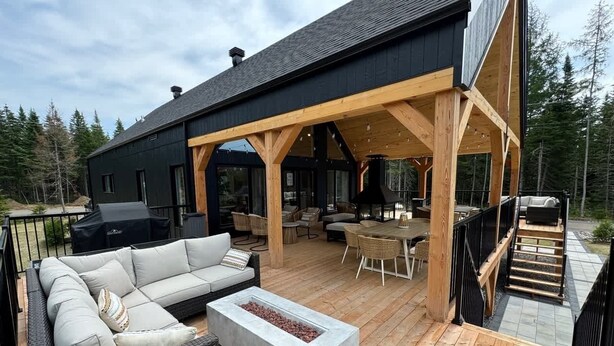 A covered outdoor patio with a sofa, a fire pit, and a dining area.