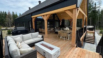 A covered outdoor patio with a sofa, a fire pit, and a dining area.