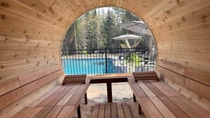 A wooden sauna with benches and a view of a swimming pool.
