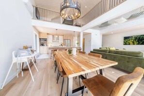 A spacious living area with a wooden dining table, a green sofa, and a kitchen in the background. - Game Room, Spa & Sauna | Le Drakkar (Shannon)