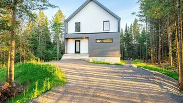 Une maison moderne à deux étages, avec une allée en gravier menant à une porte en bois.