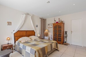 Ein Schlafzimmer mit Bett, Nachttisch, Lampe, Stuhl, Kleiderschrank und einer Tür.