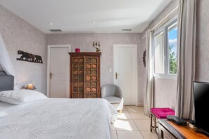 A bedroom with a bed, a wardrobe, a chair, a TV, and a window. - Room 'Le Petit Ramsès - Elephants' with Shared Pool, Wi-Fi and Air Conditioning (Sainte-Maxime)