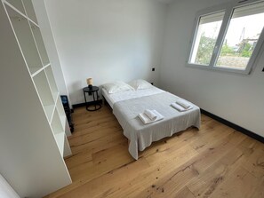 Ein Schlafzimmer mit einem Bett, einem kleinen Tisch mit einer Lampe und einem Fenster.