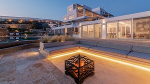 A modern house with a pool, outdoor seating, and a fire feature. - Luxury Villa Roshell (Mykonos)