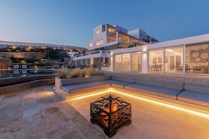 Ein modernes Haus mit Pool, Sitzgelegenheiten im Freien und einem Feuerbereich.