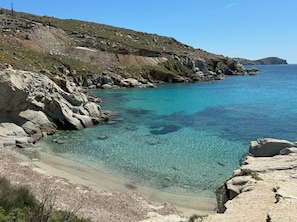 Eine Küstenlandschaft mit klarem türkisblauem Wasser, felsigen Ufern und einer hügeligen Kulisse.
