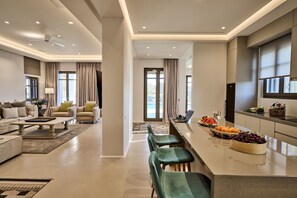 Ein modernes Wohnzimmer mit einer Couch, einem Couchtisch und einem Essbereich mit Bar und Stühlen.