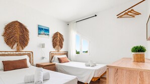 Een hotelkamer met twee bedden, een houten bureau, een hangende plant en uitzicht op het landschap.