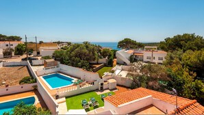 Zona residencial con piscina, césped verde y vista al mar.