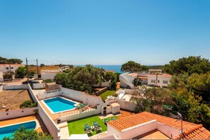 A residential area with a swimming pool, green lawn, and a view of the sea. - El Escape - Terrace and swimming pool - Menorca (Minorca)