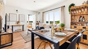 Un comedor moderno con una mesa de madera, sillas y un ventilador de techo.