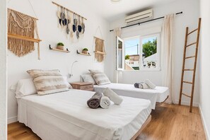 A hotel room with two beds, macramé wall hangings, a window with a view, and a wooden ladder. - El Escape - Terrace and swimming pool - Menorca (Minorca)