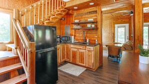 A wooden cabin interior with a kitchen, dining area, and a staircase. - Blue's Barn (Nellysford)