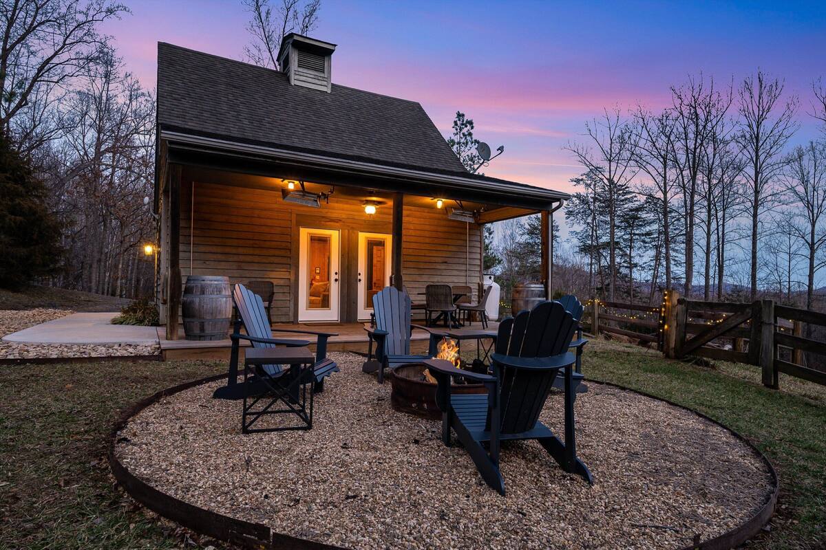 A wooden cabin with a covered porch, outdoor seating, and a fire pit.
