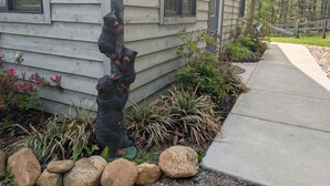 A house with a bear statue in the front yard, a pathway, and a wooden fence. - Blue's Barn (Nellysford)