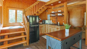 A wooden cabin interior with a kitchen, a dining area, and a staircase. - Blue's Barn (Nellysford)
