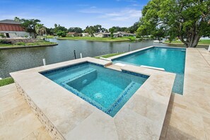 Ein rechteckiger Pool mit klarem, blauem Wasser, umgeben von einer gepflasterten Terrasse.