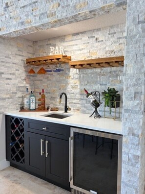Eine Küche mit Steinrückwand, Weinregal, Spüle und einem Weinkühlschrank.