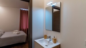 Una habitación de hotel moderna con una cama, un lavamanos blanco, un espejo y armarios de madera.
