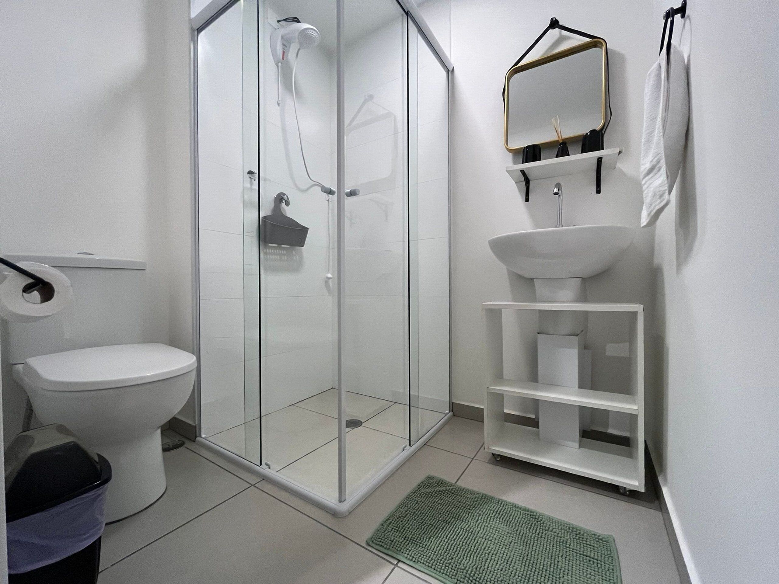 A bathroom with a toilet, a shower enclosure, a sink, and a mirror.
