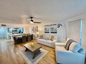 A modern living room with a sofa, coffee table, and dining area. - Grand Deluxe Bay 3BR Penthouse near Disney (Kissimmee)