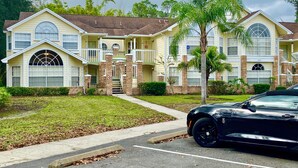 Un bâtiment à deux étages doté d’une entrée centrale, d’un porche couvert et d’un parking où se trouve une voiture noire.