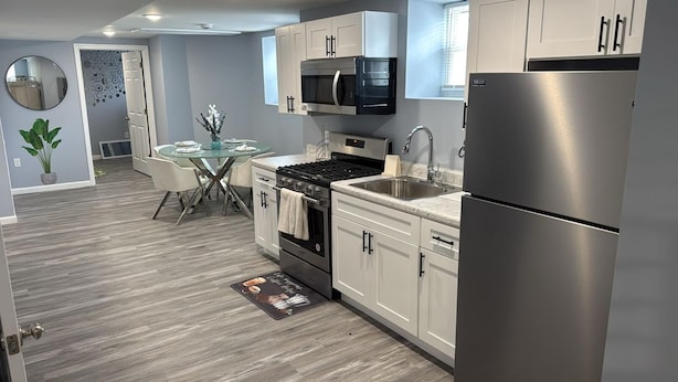 Una cocina moderna con electrodomésticos de acero inoxidable, armarios blancos y una mesa de comedor de vidrio.