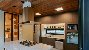 Une cuisine moderne dotée d’un îlot central, d’appareils électroménagers intégrés et d’un plafond en bois.
