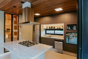A modern kitchen with a central island, built-in appliances, and a wooden ceiling.