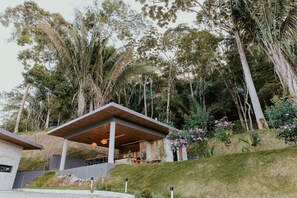 A modern building with a covered outdoor area, surrounded by trees and greenery.