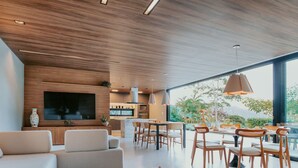 Un salon moderne comprenant un canapé, un coin repas et un téléviseur fixé au mur.