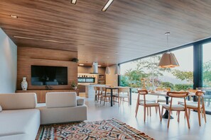A modern living room with a sofa, dining area, and a TV mounted on the wall.