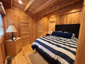 Ein Schlafzimmer mit Holzwänden, einem Bett, Nachttischen und einem Fenster.
