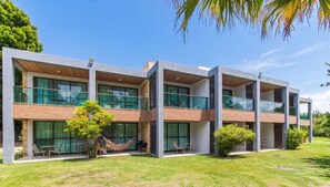 A modern multi-story building with large windows, outdoor seating, and a hammock. - Studio c Piscina e Quadras em Barra de S o Miguel (Barra de São Miguel)