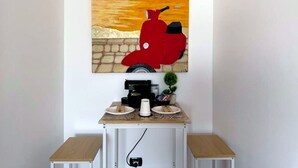 Ein Zimmer mit einem Wandbild eines roten Stiers, einer Kaffeemaschine und einem kleinen Topfpflanzen.