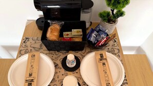 Ein Tisch ist gedeckt mit Tellern, Servietten, einem kleinen Dekoartikel und einer Kaffeemaschine.